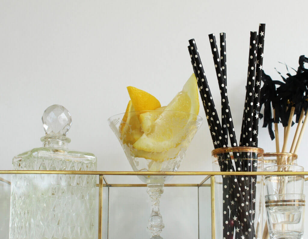 Bar cart with a jar, lemon slices in a glass, and black straws in the Oklahoma City metro area home