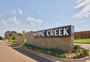 Pine Creek entrance sign in Oklahoma City, featuring a welcoming design and natural surroundings.