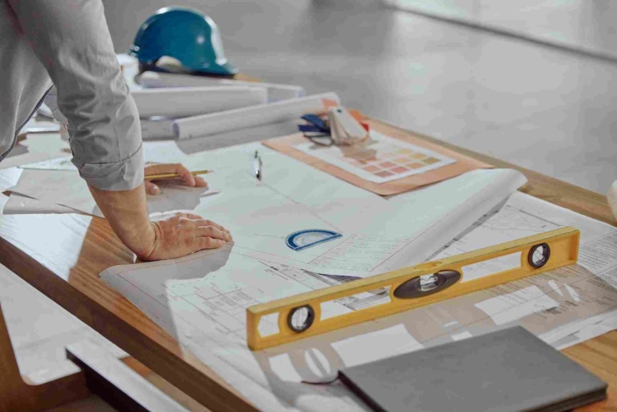 A person's hand on a table with a ruler and a blueprint Norman, Oklahoma