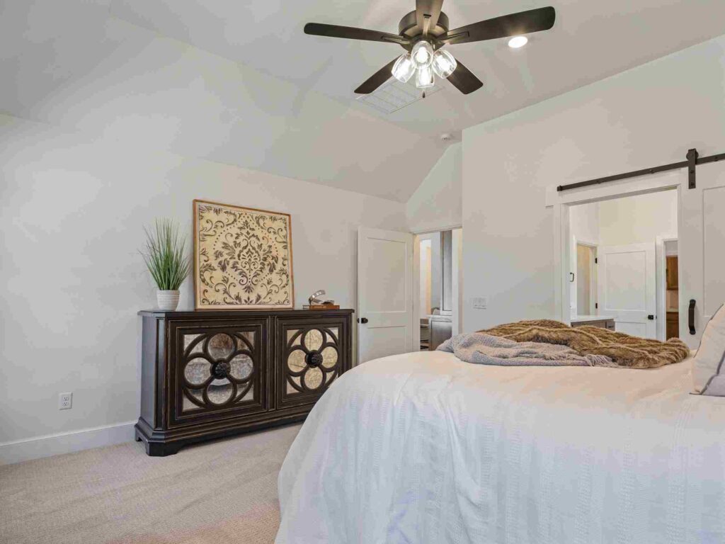 A well-lit bedroom in Oklahoma City with a ceiling fan above a neatly made bed