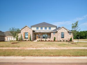 Two-story brick home with covered porch, lawn & Chloe floor plan in the Oklahoma City metro area.