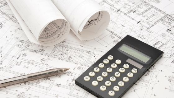 architectural blueprints, a calculator, and a pen for home construction planning in Oklahoma City