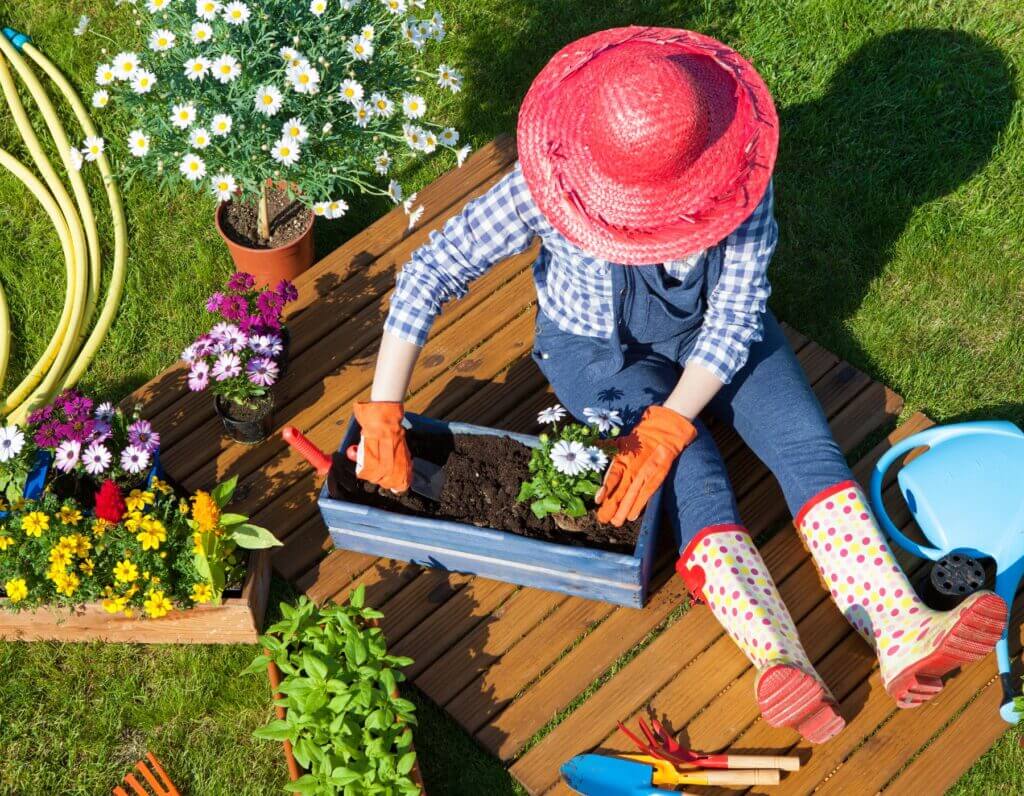 Girl gardening on a wooden deck with flowers, pots, and tools in the Oklahoma City metro area
