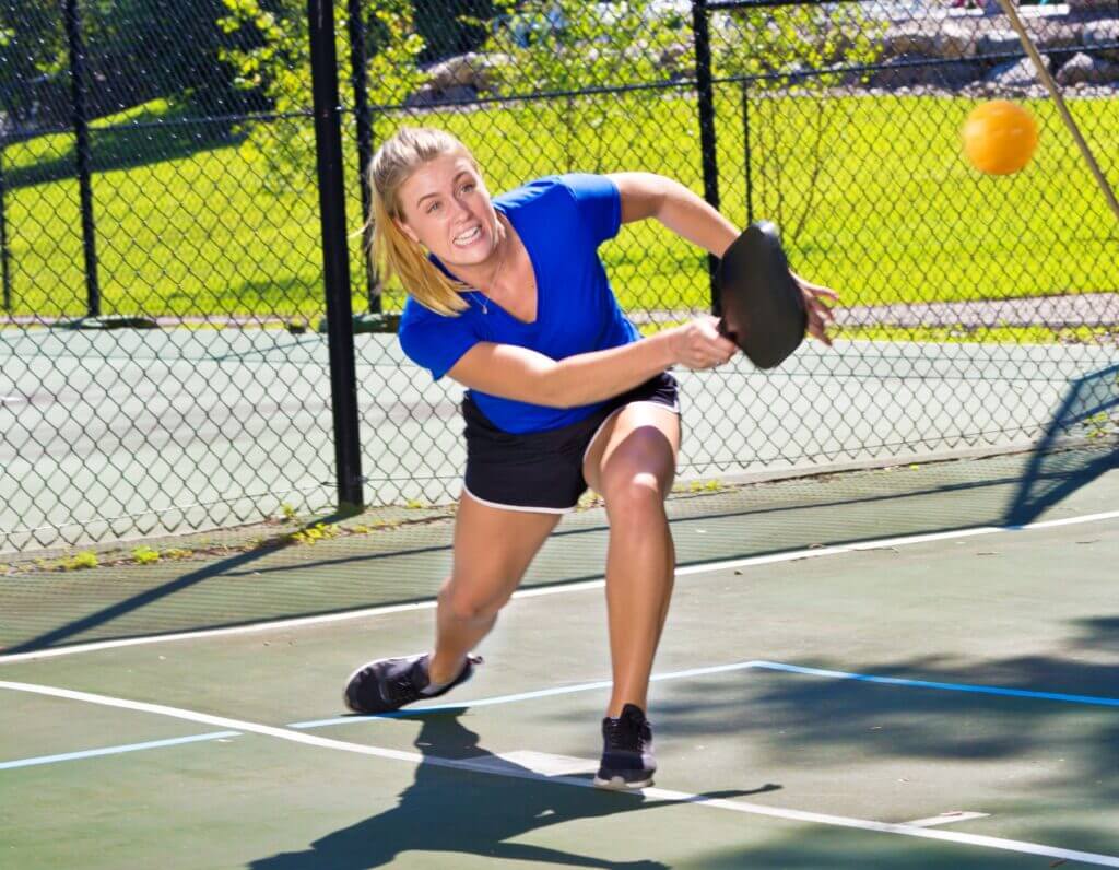 Young girl Player lunging forward on a court to hit a pickleball in the Oklahoma City metro area
