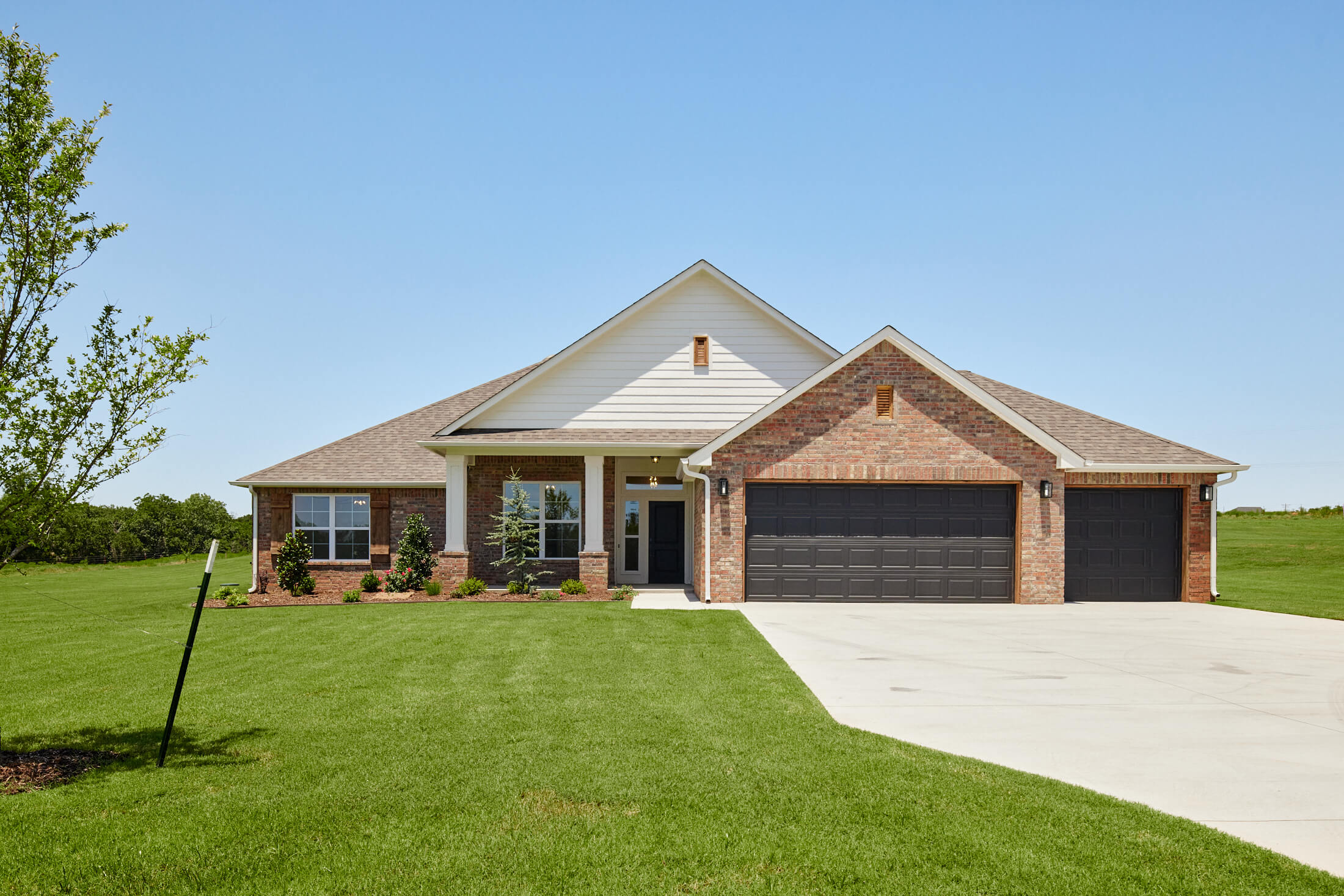 House with a large garage and green lawn built on an owned lot in the Oklahoma City metro area