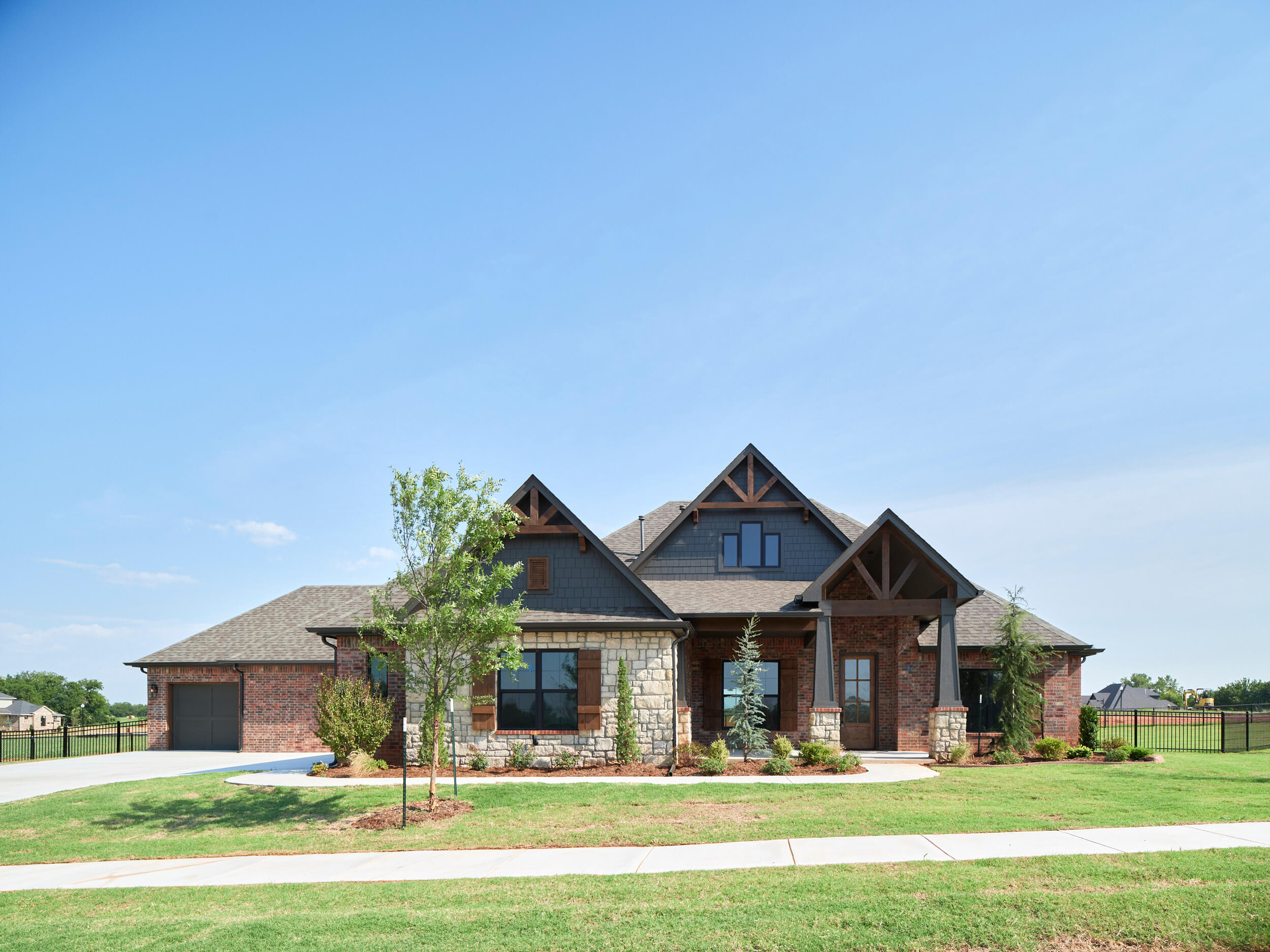 Large stone house built on owned lot with a landscaped front yard in the Oklahoma City metro area