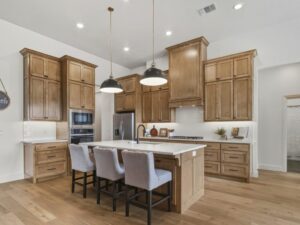 Kitchen with wood cabinetry, large island seating, and pendant lights in Oklahoma City metro area