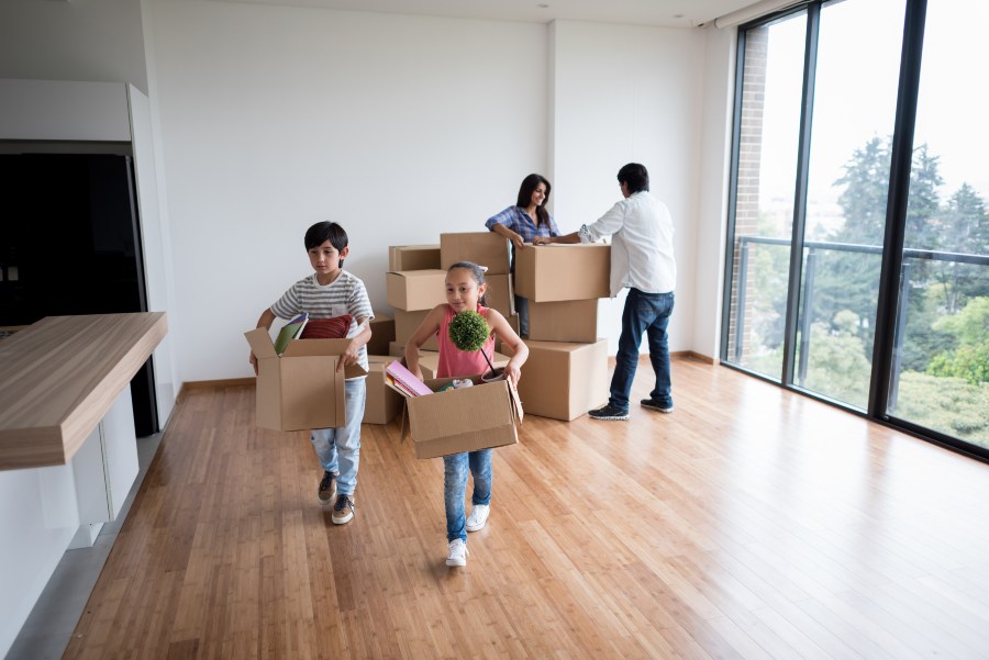 Family carrying moving boxes into a new home during move-in day